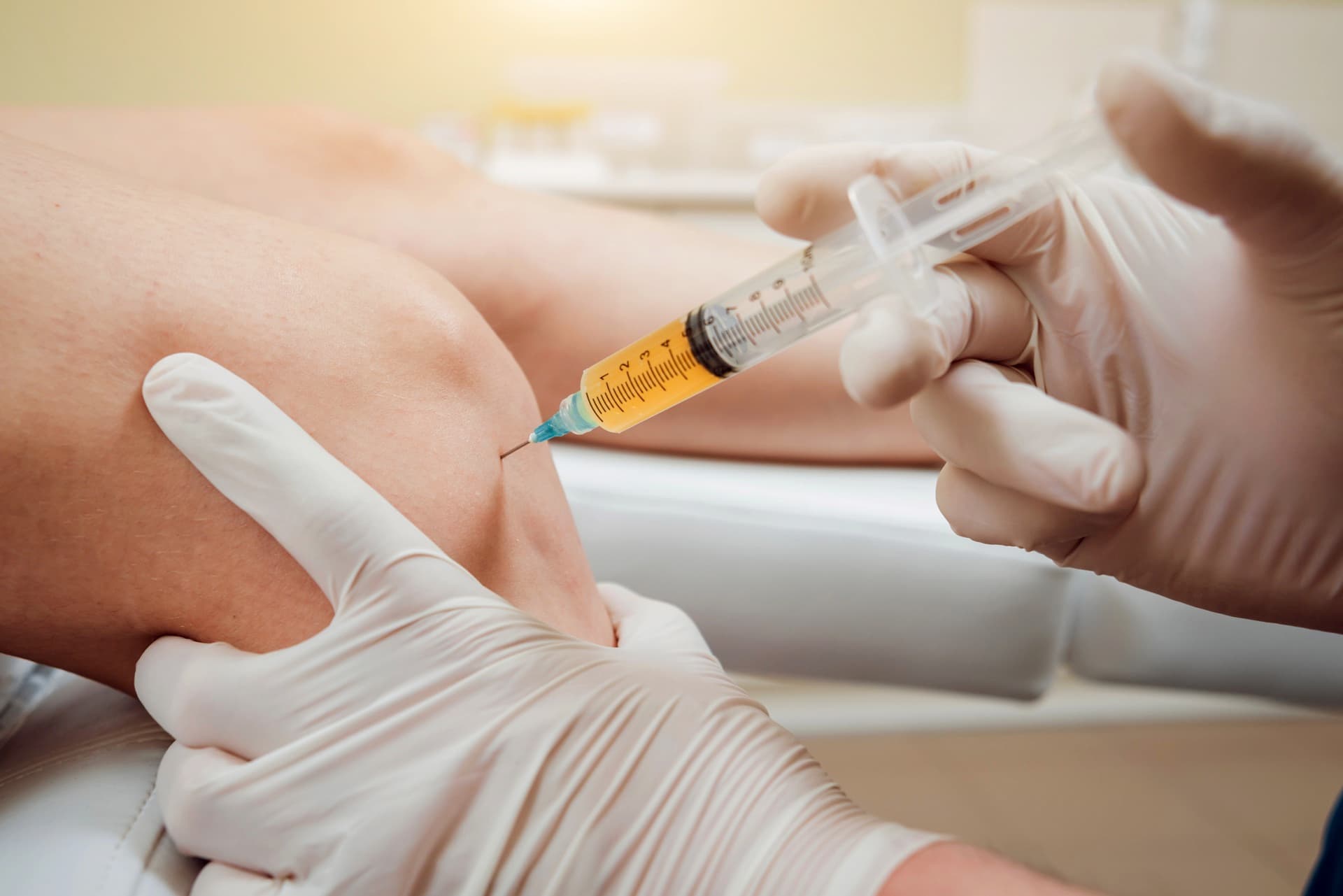Clinician performing ultrasound-guided knee injection in specialist practice